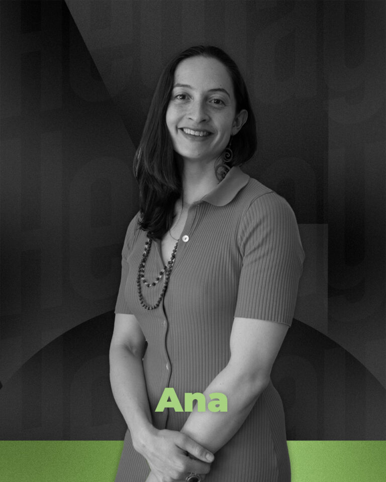 Smiling woman in a collared dress with a beaded necklace, standing with hands clasped. Text: "Ana".