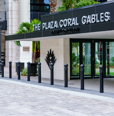 Entrance of The Plaza Coral Gables with decorative pillars and greenery.